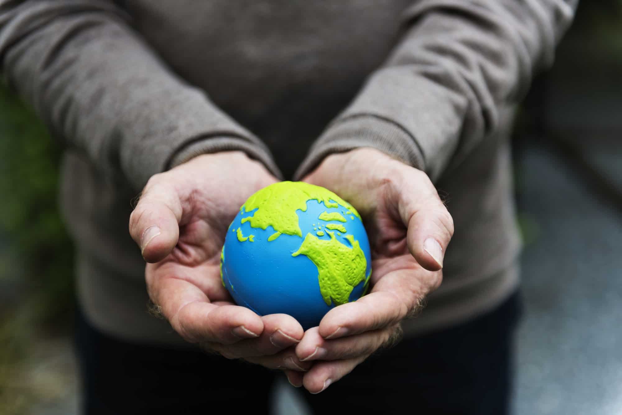 Hands holding a clay globe planet Earth